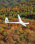 a glider flying over a mountain ridge in Autumn
